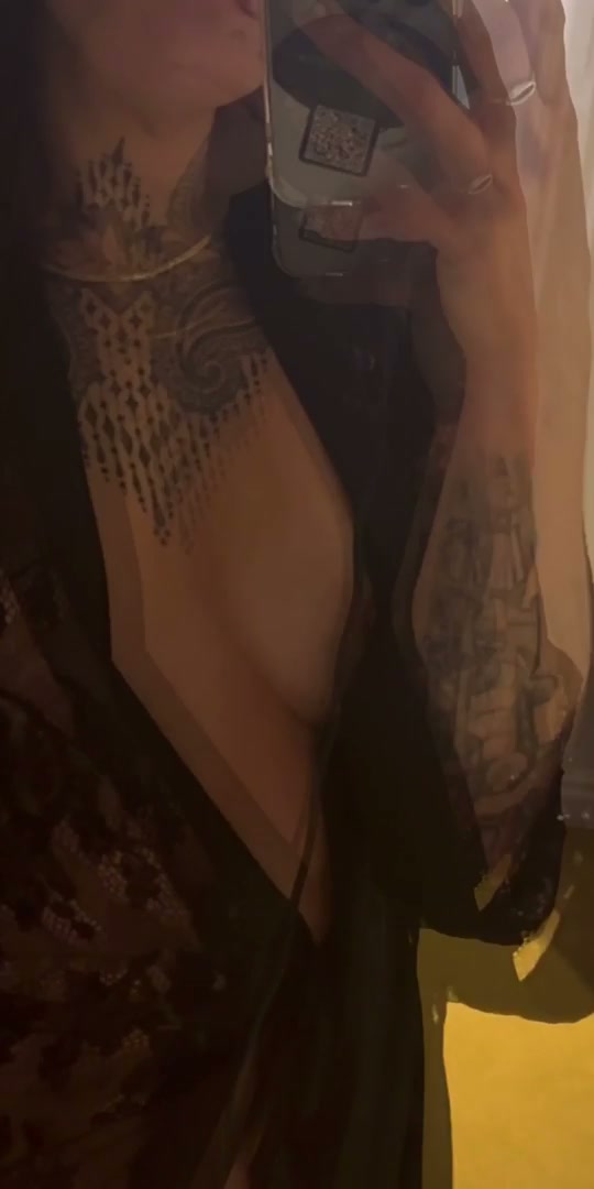 Alluring Nara Domingos in a black lace robe, showcasing chest tattoos in a mirror selfie.